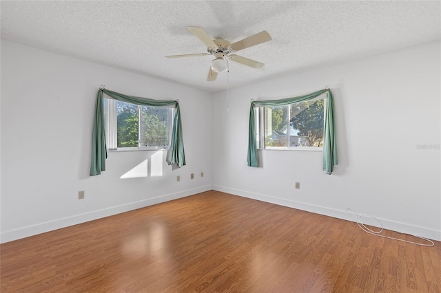 empty room with a healthy amount of sunlight, a textured ceiling, and hardwood / wood-style flooring