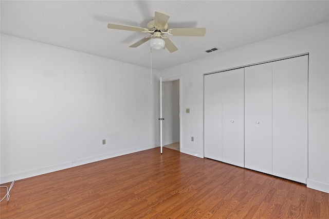 unfurnished bedroom with hardwood / wood-style flooring, ceiling fan, a textured ceiling, and a closet