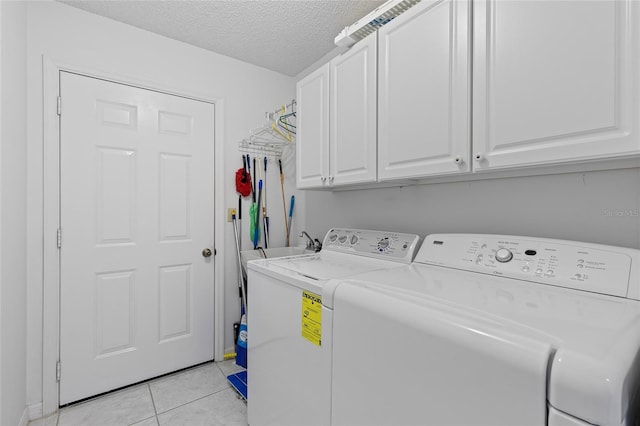 clothes washing area with cabinets, light tile patterned floors, a textured ceiling, and independent washer and dryer