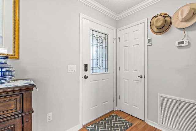 entryway with ornamental molding, a textured ceiling, and light wood-type flooring