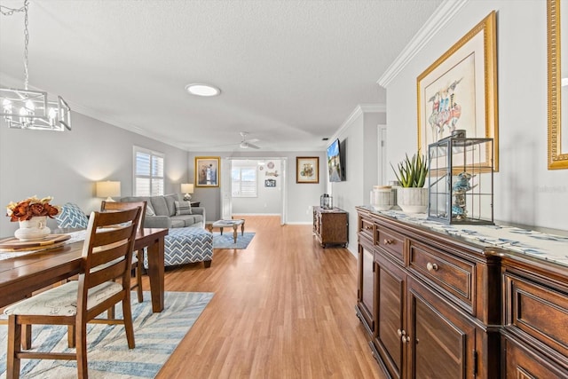 dining area with a textured ceiling, ceiling fan with notable chandelier, light hardwood / wood-style floors, and crown molding