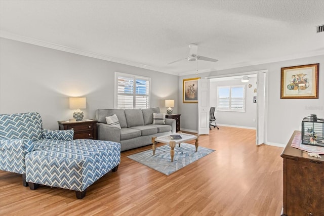 living room featuring ceiling fan, wood-type flooring, a textured ceiling, and ornamental molding