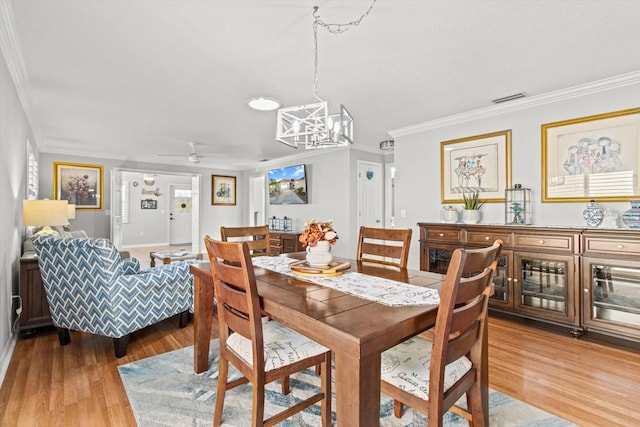 dining area with hardwood / wood-style floors, ceiling fan with notable chandelier, and ornamental molding