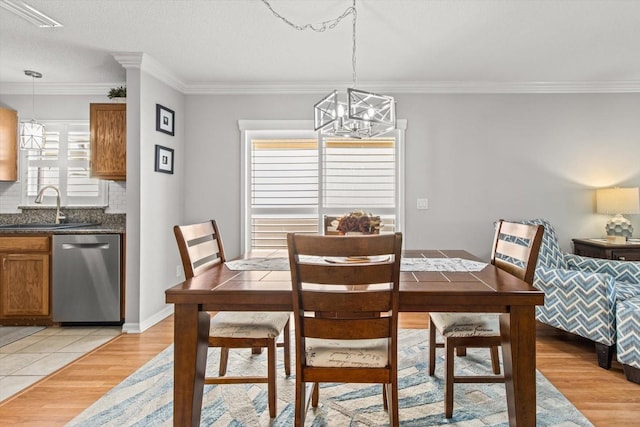 dining room featuring sink, a notable chandelier, crown molding, a textured ceiling, and light wood-type flooring