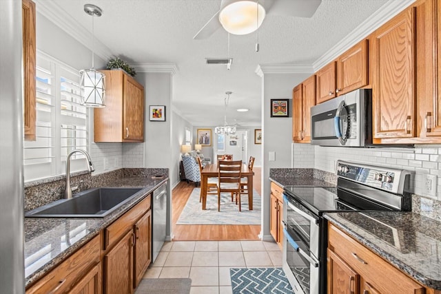 kitchen with a textured ceiling, sink, stainless steel appliances, and hanging light fixtures