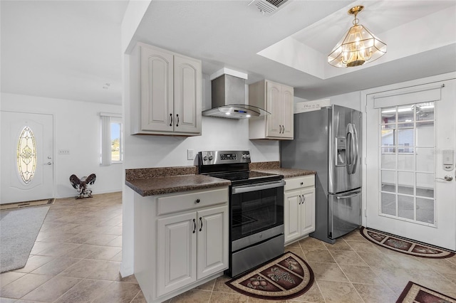 kitchen featuring light tile patterned flooring, stainless steel appliances, hanging light fixtures, and wall chimney range hood