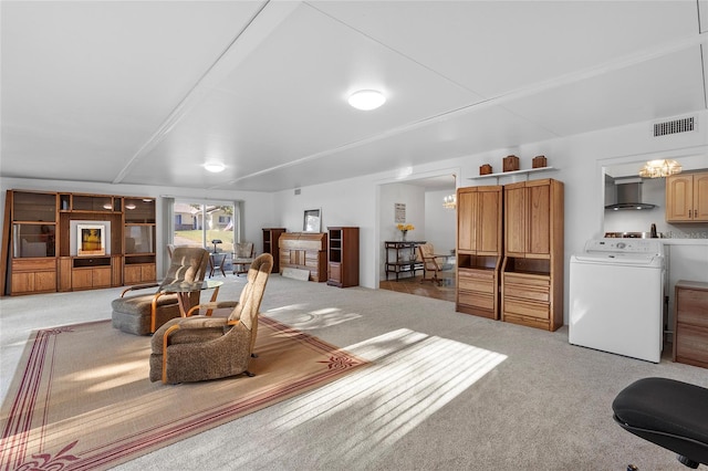 living room with carpet floors, washer / clothes dryer, and an inviting chandelier