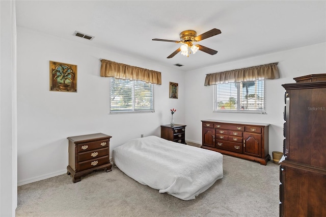 bedroom featuring ceiling fan, light colored carpet, and multiple windows