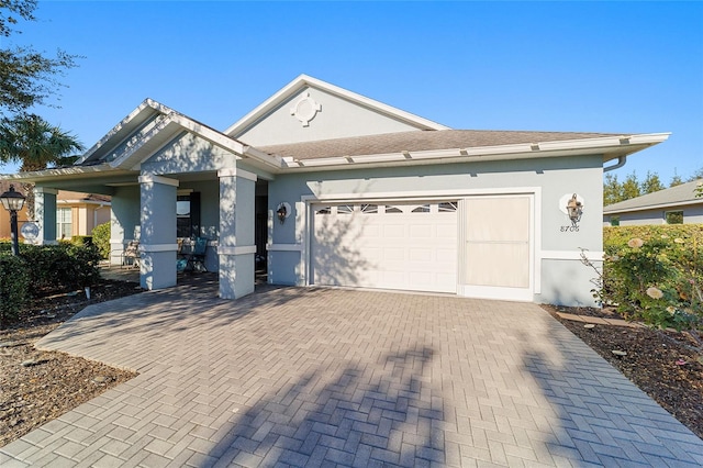 view of front facade with a garage, decorative driveway, and stucco siding