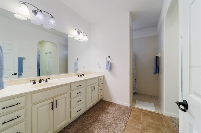 bathroom featuring tile patterned flooring, vanity, and tiled shower