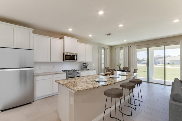 kitchen featuring white cabinets, stainless steel appliances, a kitchen island with sink, and sink