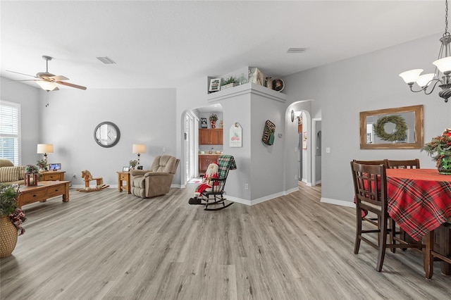 dining room with ceiling fan with notable chandelier and light wood-type flooring