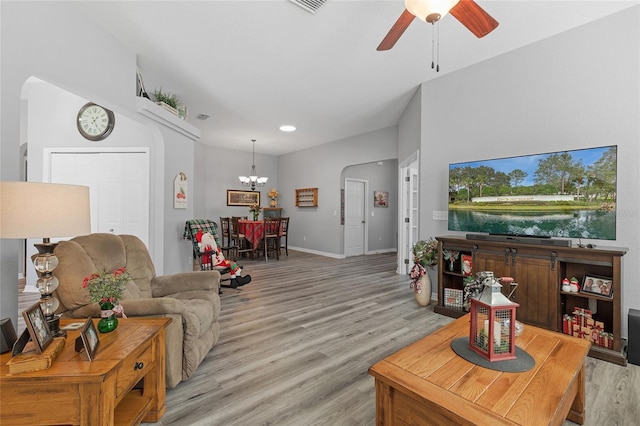 living room with ceiling fan with notable chandelier and light hardwood / wood-style floors