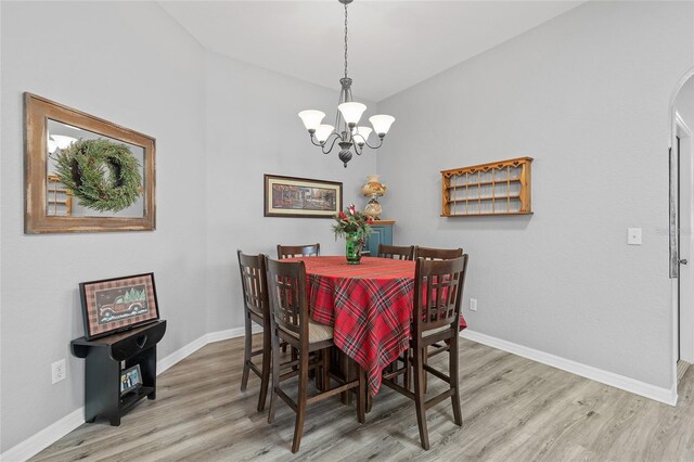 dining room featuring wood-type flooring, lofted ceiling, and an inviting chandelier