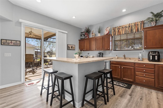 kitchen with light hardwood / wood-style flooring, a wealth of natural light, a breakfast bar area, and sink