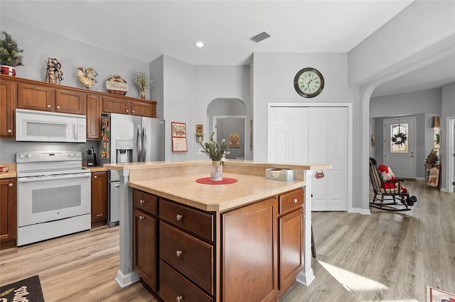 kitchen with light wood-type flooring, white appliances, and a center island