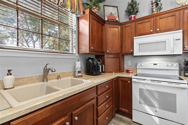 kitchen featuring light wood-type flooring, white appliances, and sink