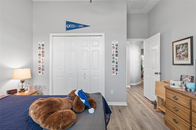 bedroom with a towering ceiling, light hardwood / wood-style flooring, and a closet