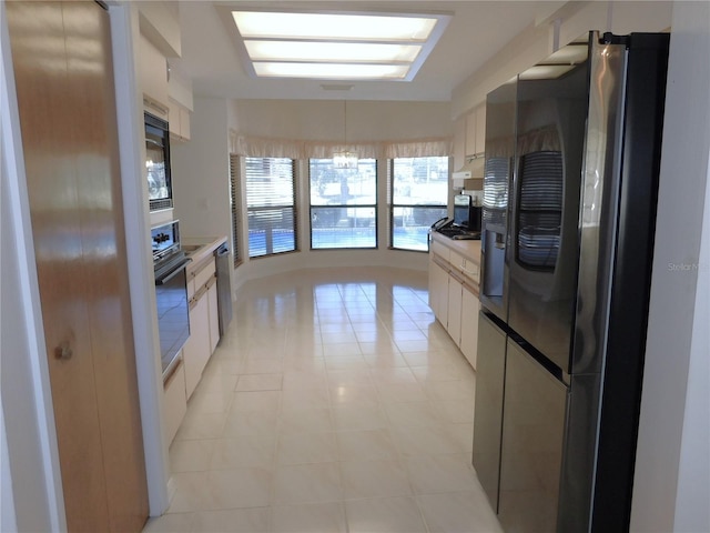 kitchen featuring white cabinets, light tile patterned floors, stainless steel appliances, and an inviting chandelier