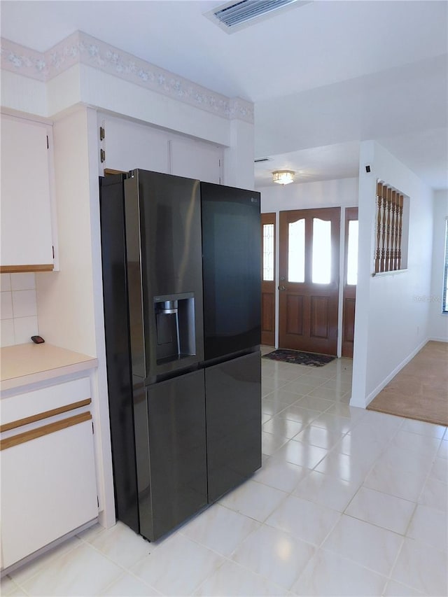 kitchen featuring black fridge with ice dispenser, white cabinets, and light tile patterned floors