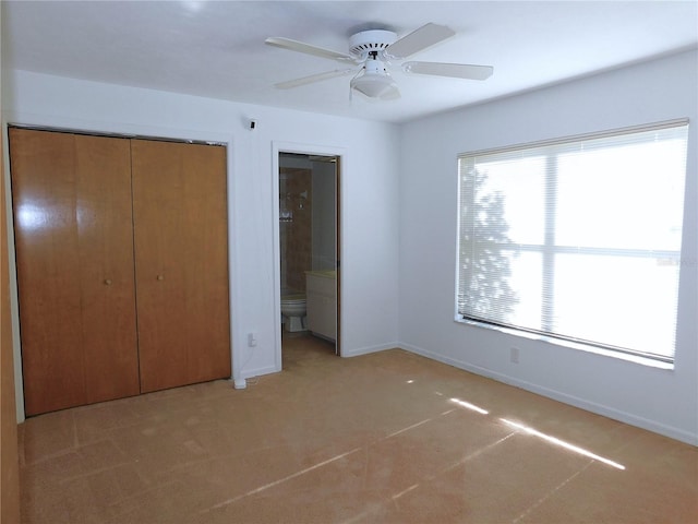 unfurnished bedroom with carpet, ceiling fan, connected bathroom, and a closet