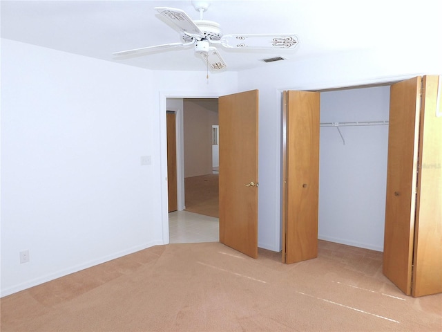 unfurnished bedroom featuring ceiling fan, a closet, and light carpet