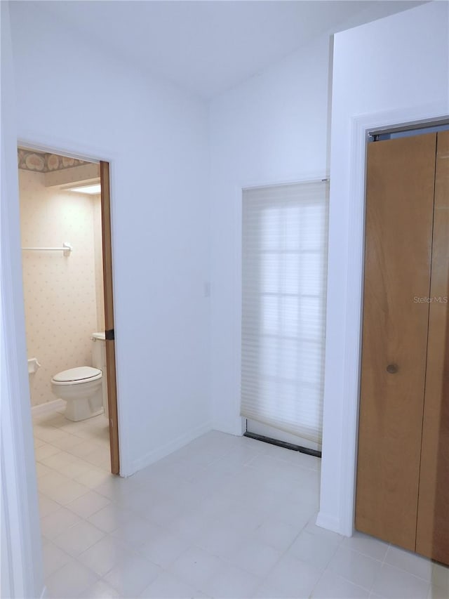 unfurnished bedroom featuring ensuite bath, a closet, and light tile patterned floors