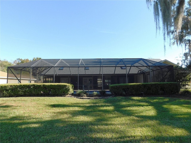 rear view of house with a lanai and a lawn