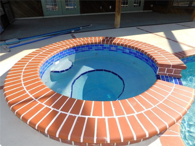 view of pool featuring an in ground hot tub, a patio, and french doors