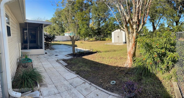 view of yard with a shed, a patio area, and a sunroom