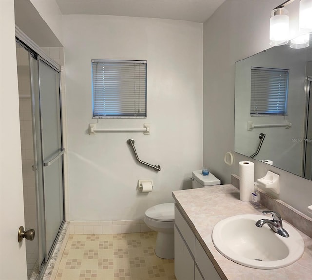 bathroom with tile patterned floors, vanity, an enclosed shower, and toilet