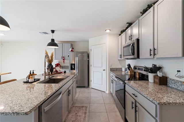 kitchen featuring pendant lighting, a kitchen island with sink, sink, light tile patterned floors, and appliances with stainless steel finishes