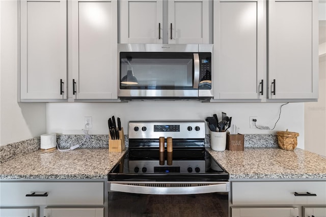 kitchen featuring light stone countertops, appliances with stainless steel finishes, and white cabinetry