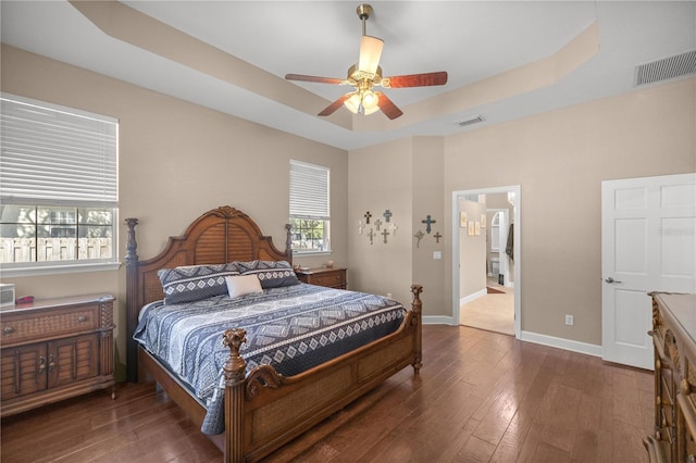 bedroom featuring dark hardwood / wood-style flooring, a tray ceiling, and ceiling fan