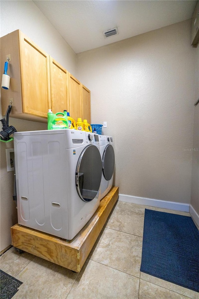 laundry area with light tile patterned flooring, cabinets, and washing machine and clothes dryer