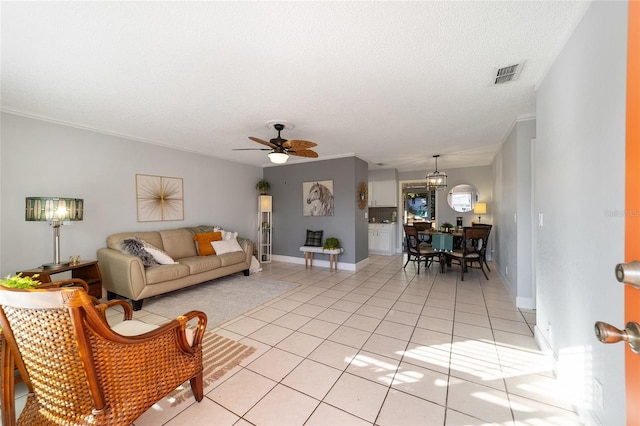 living room with ceiling fan, light tile patterned floors, a textured ceiling, and ornamental molding