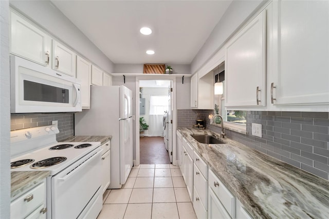 kitchen featuring white cabinetry, sink, light stone countertops, white appliances, and light tile patterned flooring