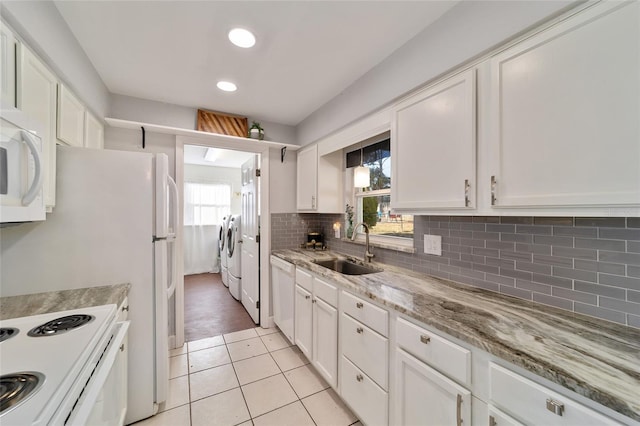 kitchen with white cabinetry, sink, light tile patterned floors, and washer and dryer