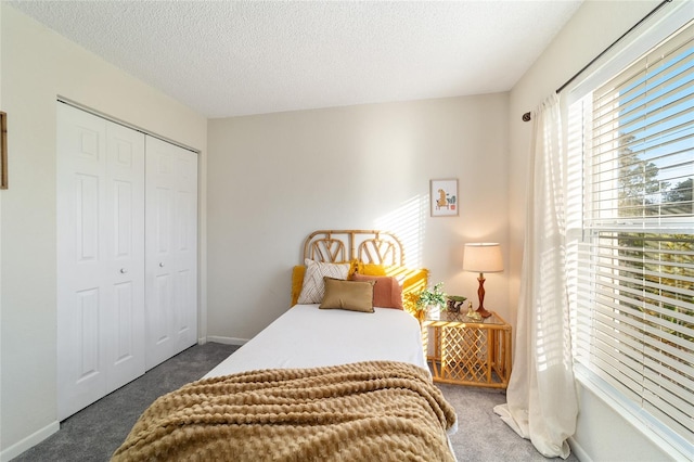 bedroom with a closet, a textured ceiling, and dark colored carpet