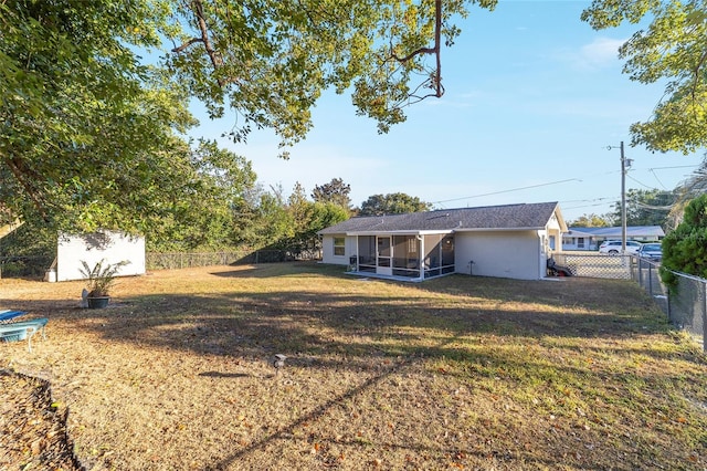 back of house featuring a lawn, a sunroom, and a storage shed