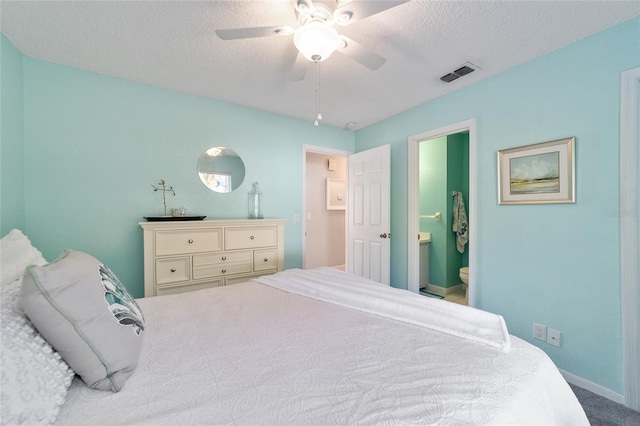 carpeted bedroom featuring ceiling fan, ensuite bathroom, and a textured ceiling