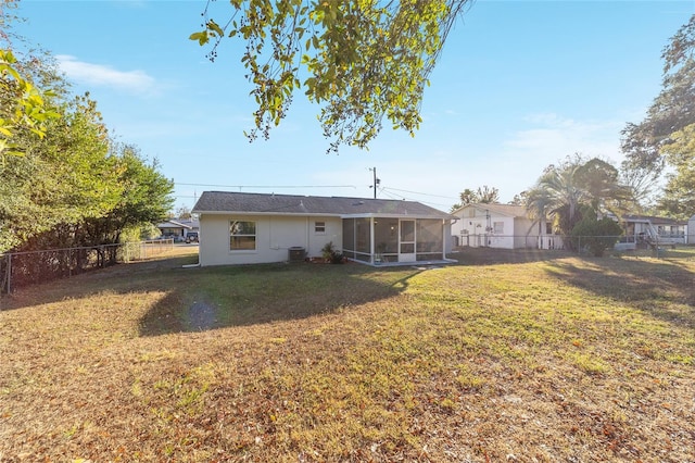 rear view of property with a sunroom, central AC unit, and a yard