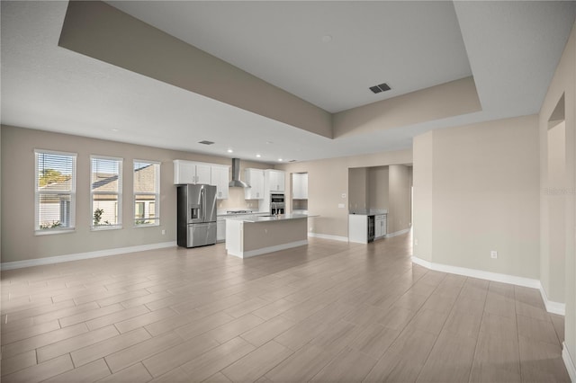 unfurnished living room featuring light wood-type flooring and a tray ceiling