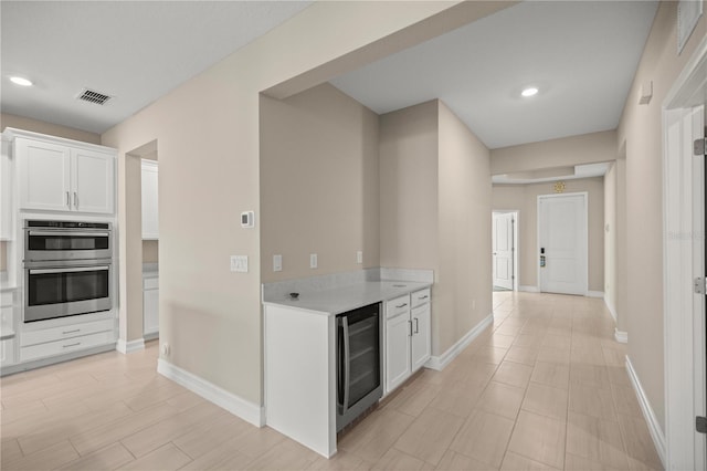 kitchen featuring wine cooler, white cabinets, and stainless steel double oven