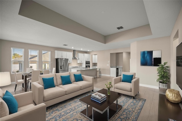 living room featuring a tray ceiling and light hardwood / wood-style flooring