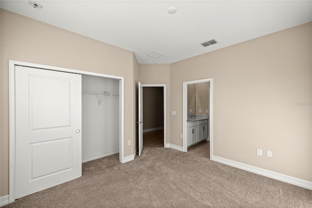 unfurnished bedroom with light carpet, connected bathroom, and a closet