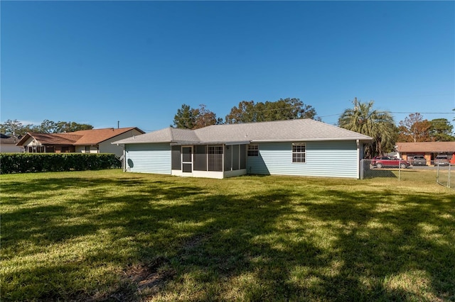 rear view of property with a lawn and a sunroom