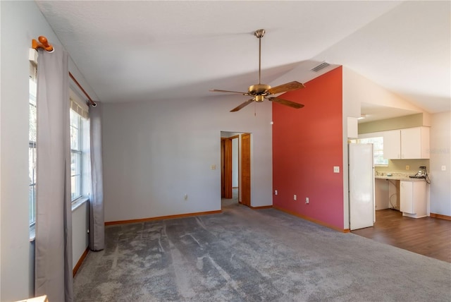 unfurnished living room featuring ceiling fan, dark carpet, and lofted ceiling