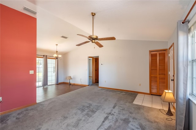 carpeted spare room featuring ceiling fan with notable chandelier and lofted ceiling