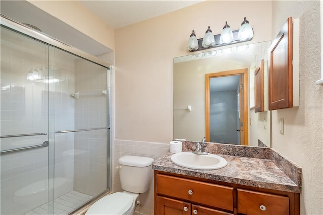 bathroom featuring vanity, toilet, and a shower with door